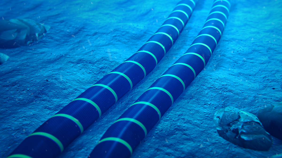 Two large, parallel subsea cables with blue and black stripes rest on the sandy ocean floor in a 3D-rendered image.
