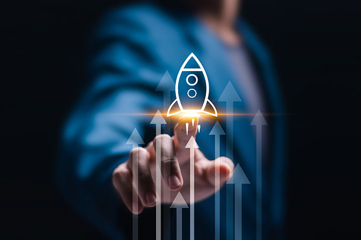 A businessman's hand touching a virtual glowing rocket icon, symbolizing fast startup growth, with upward arrows in the background representing strategic planning and business success.