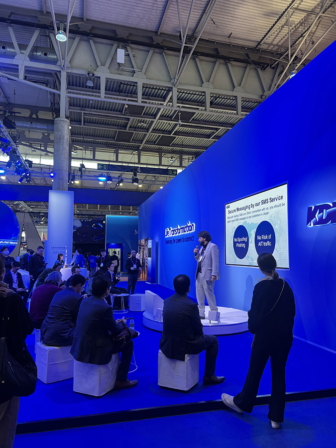 A presentation with an audience seated and standing, watching the speaker.