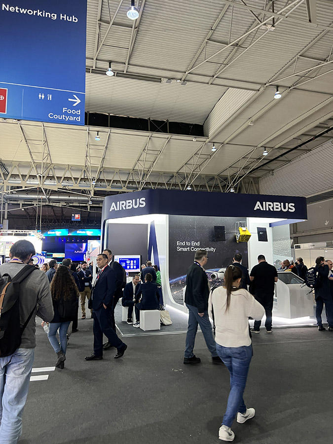 Visitors walking past the Airbus booth with a display themed 'End to End Smart Connectivity'.