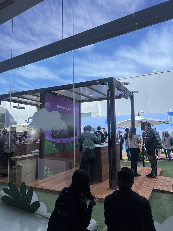 A networking area at a conference with attendees and a booth sign reading 'Meet our experts.'