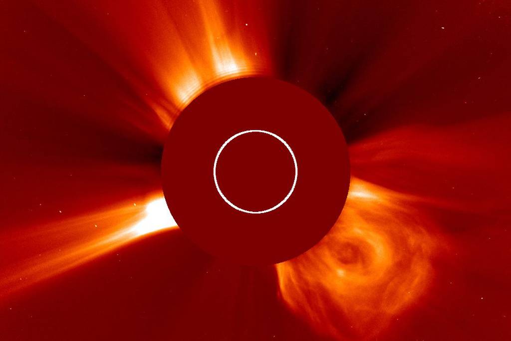 Image of a coronal mass ejection from the sun, showing bright, fiery streams of plasma radiating outwards, captured in visible light.