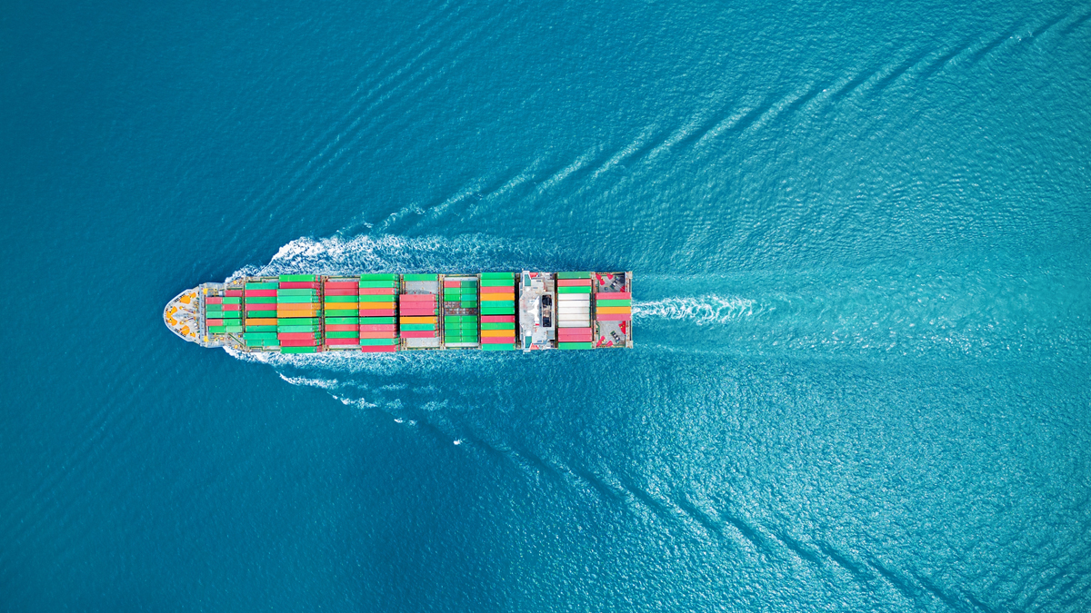 Overhead view of a cargo ship with colorful containers in blue water.