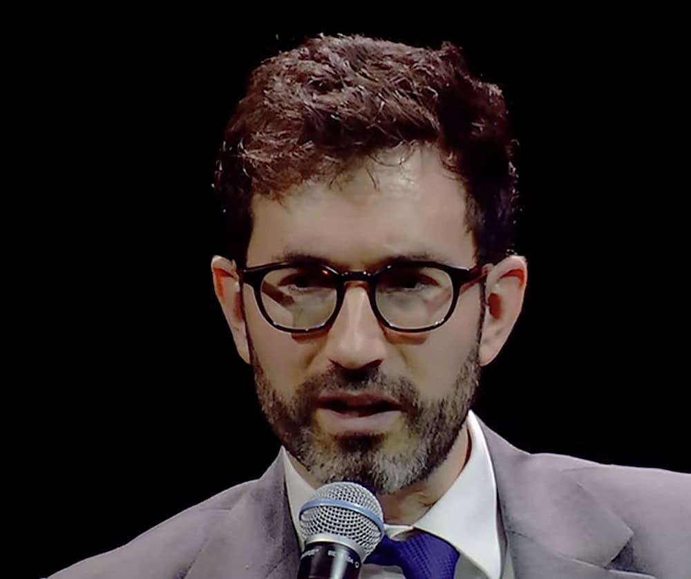 Arianespace CEO David Cavaillolès, wearing glasses, speaks into a microphone during a presentation at the PAF 2025 conference.