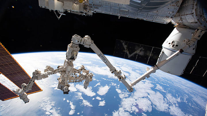The International Space Station's Canadarm2 and robotic hand, Dextre, demonstrate the potential of automation and robotics in space. SpaceX Dragon cargo ship pictured in the upper right.