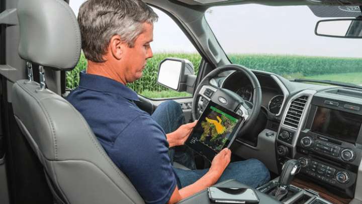 Farm worker using a tablet in a car