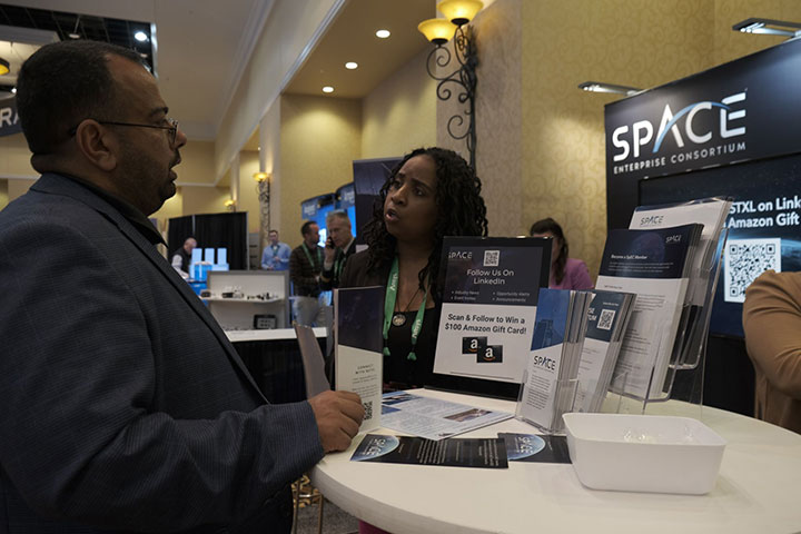 SpEC personnel at a space industry trade show explaining their role in bridging the cultural gap between military buyers and commercial space startups.