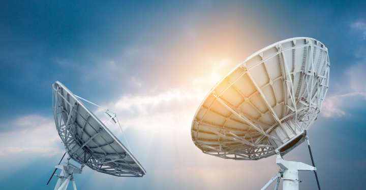 Two satellite dishes pointing at the sky during the day